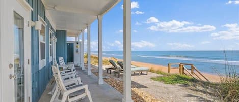 Relax on the covered porch with ocean views, surrounded by comfortable seating.