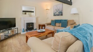 A living room with a fireplace, sofa, and television. - The Old Mill (Keswick)
