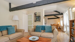 A cozy living room with two beige sofas, a wooden coffee table, and a bookshelf. - The Old Mill (Keswick)