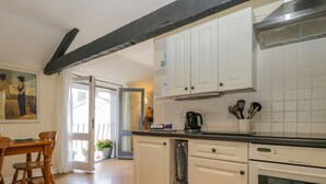 A kitchen with white cabinets, a black countertop, and a dishwasher. - The Old Mill (Keswick)