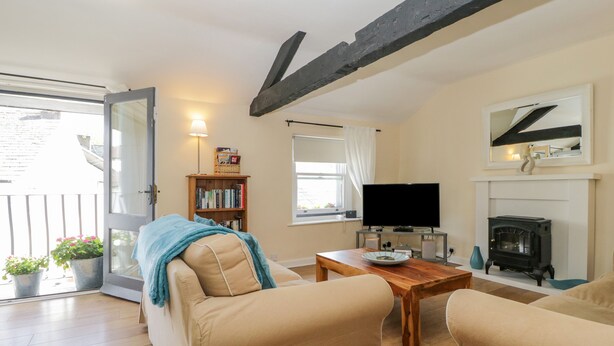 A cozy living room with a sofa, a coffee table, a fireplace, and a television. - The Old Mill (Keswick)