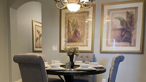 A dining room with a round table, four chairs, a chandelier, and framed artwork on the walls. - Paradise Villa in Regal Palms (Davenport)