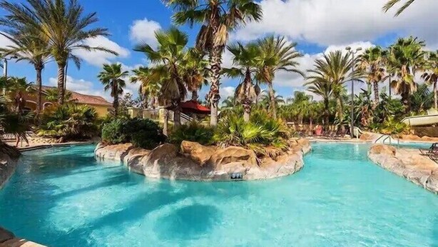 A pool area with clear blue water, surrounded by palm trees and rocks. - Paradise Villa in Regal Palms (Davenport)