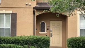 A two-story building with a beige facade, a brown door, and a small window above it. - Paradise Villa in Regal Palms (Davenport)