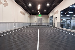 Un grand espace intérieur doté d’un sol à carreaux, d’une porte de sortie centrale et d’appareils de musculation à l’arrière-plan.