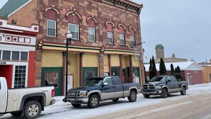 A building with a red and yellow facade, a firehouse on the left, and two trucks parked in front. - Spacious 4-bedroom at La Casa della Nonnina (Negaunee)
