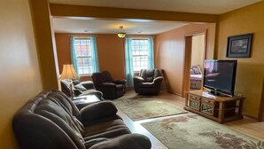 A living room with a sofa set, a television, and a wooden cabinet. - Spacious 4-bedroom at La Casa della Nonnina (Negaunee)