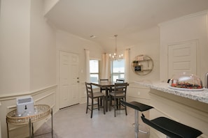 A kitchen with a dining table, chairs, a chandelier, a buffet, and a refrigerator.