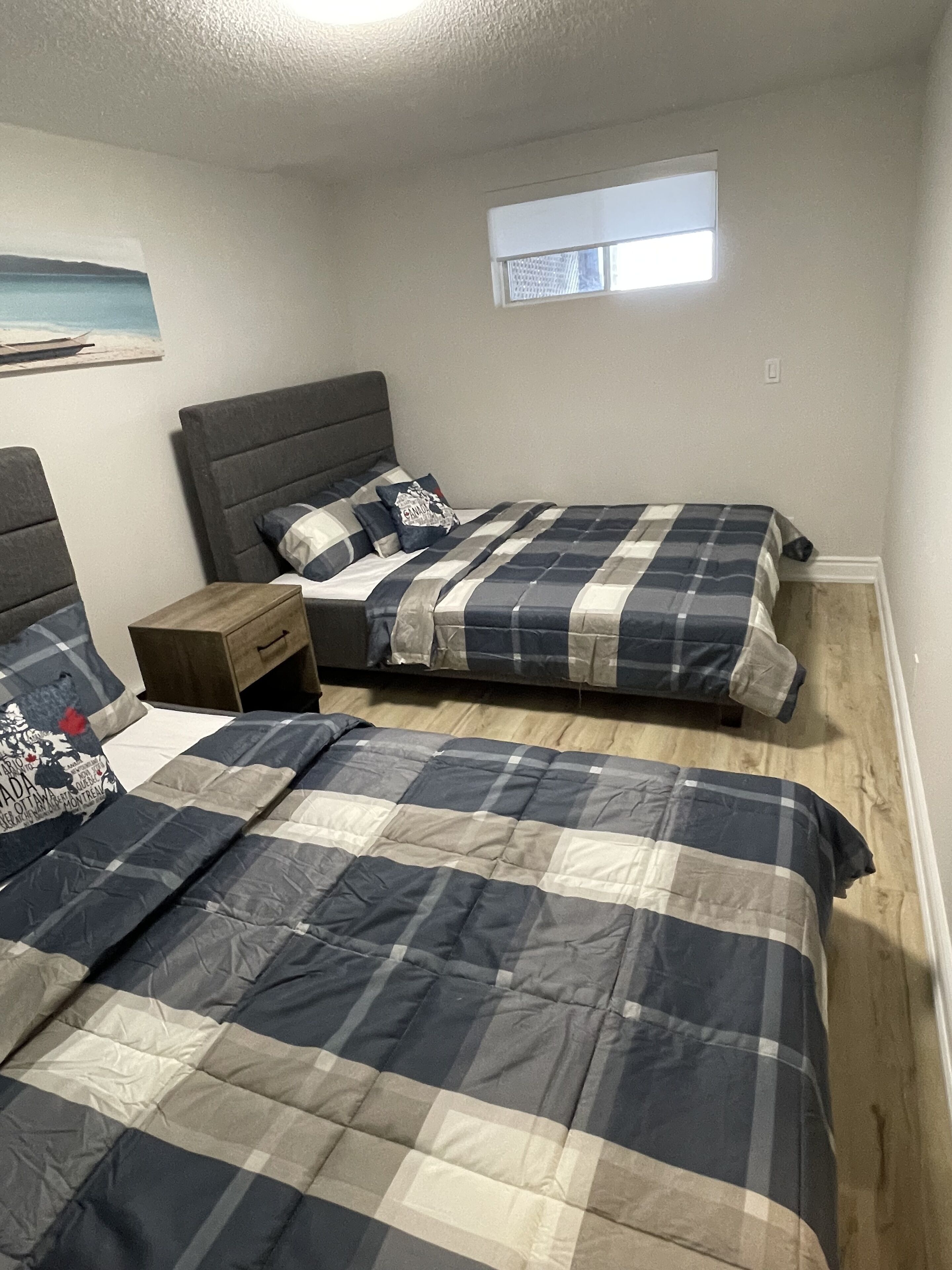 Een slaapkamer met twee bedden, een nachtkastje en een klein raam.