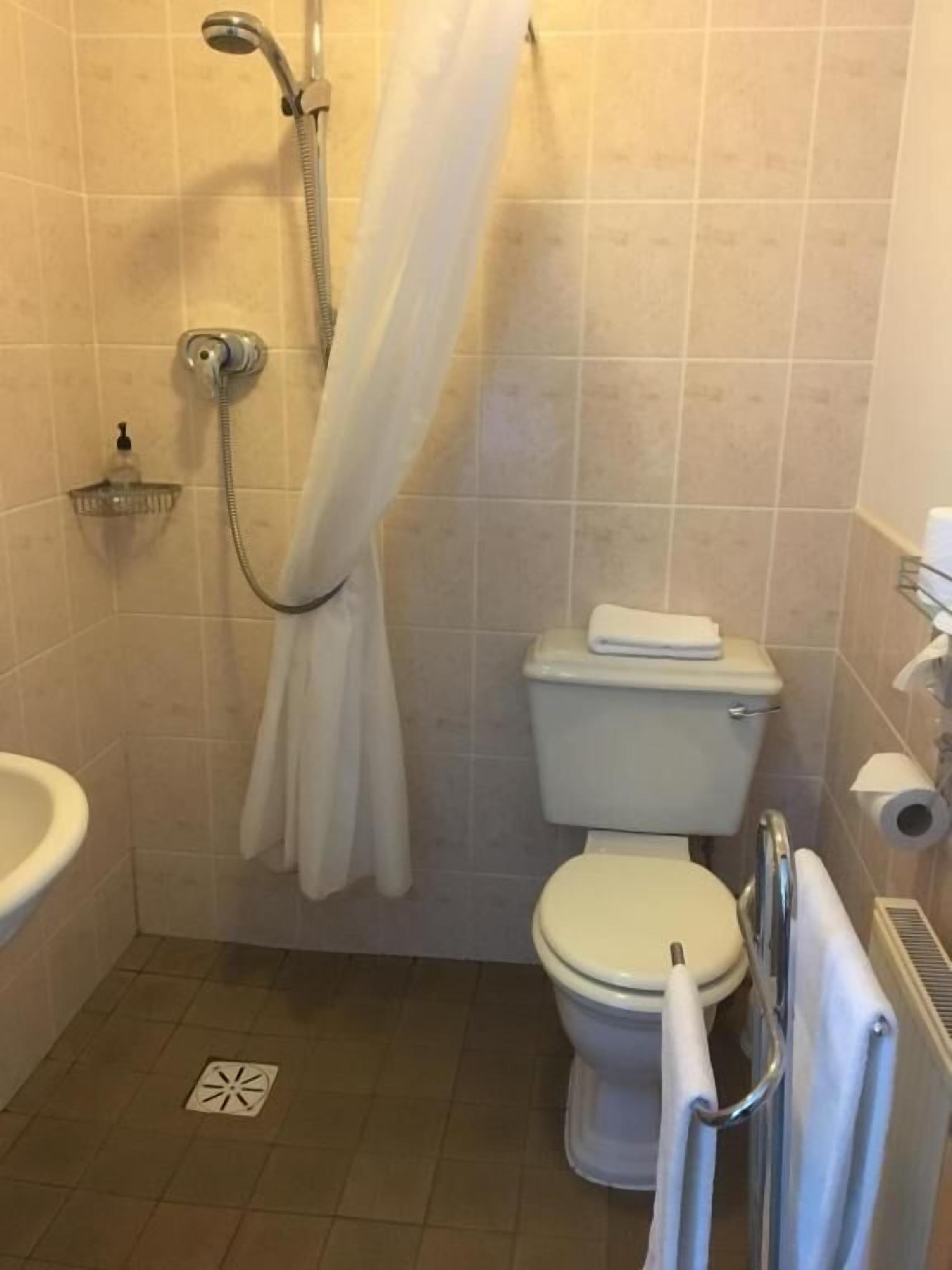 Un baño pequeño y limpio con ducha, inodoro y lavamanos.