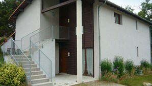 A two-story building with a staircase leading to a balcony, a front door, and a small porch area.