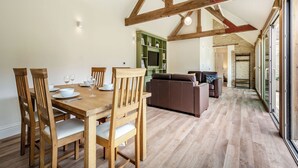 Un área de comedor con sillas de madera y una mesa, un mueble de entretenimiento verde y una pared de piedra.