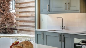 Una cocina moderna con armarios grises, encimera blanca y horno empotrado.