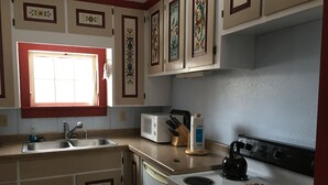 A kitchen with a sink, microwave, stove, and decorative tiles. - "Little House on the Prairie" with modern plumbing! (Coon Valley)