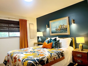 A hotel room with a bed, a nightstand, a lamp, a window with curtains, and a painting on the wall. - Well-furnished Hiker's Retreat, Centrally located for visiting the ONP; Sleeps 8 (Port Angeles)