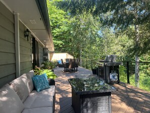 Een terras buiten met een bank, stoelen en een barbecue.