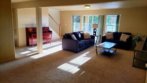 A living room with a piano, a sofa, a coffee table, and a staircase leading to another room. - 5 Bedroom home near downtown with hot tub! (Colorado Springs)