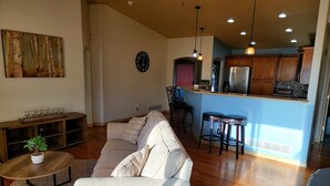 A spacious living room with a sofa, a coffee table, and a dining area with stools. - 5 Bedroom home near downtown with hot tub! (Colorado Springs)