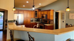 A modern kitchen with wooden cabinets, stainless steel appliances, and pendant lighting. - 5 Bedroom home near downtown with hot tub! (Colorado Springs)