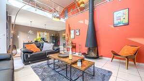 Una sala de estar moderna con chimenea, un sofá, una mesa de centro y un comedor al fondo.