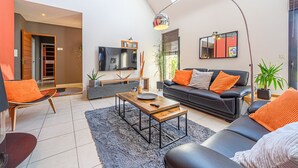 Una sala moderna con un sofá de cuero negro, una mesa de centro de madera y un televisor montado en la pared.