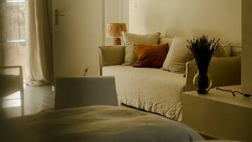 Une chambre à coucher avec un grand lit, un canapé et une petite table sur laquelle est posé un vase.