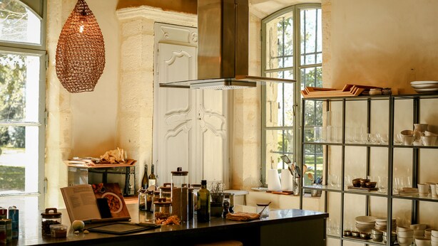 Een keuken met een hanglamp, een centraal kookeiland en een glazen serviesrek.