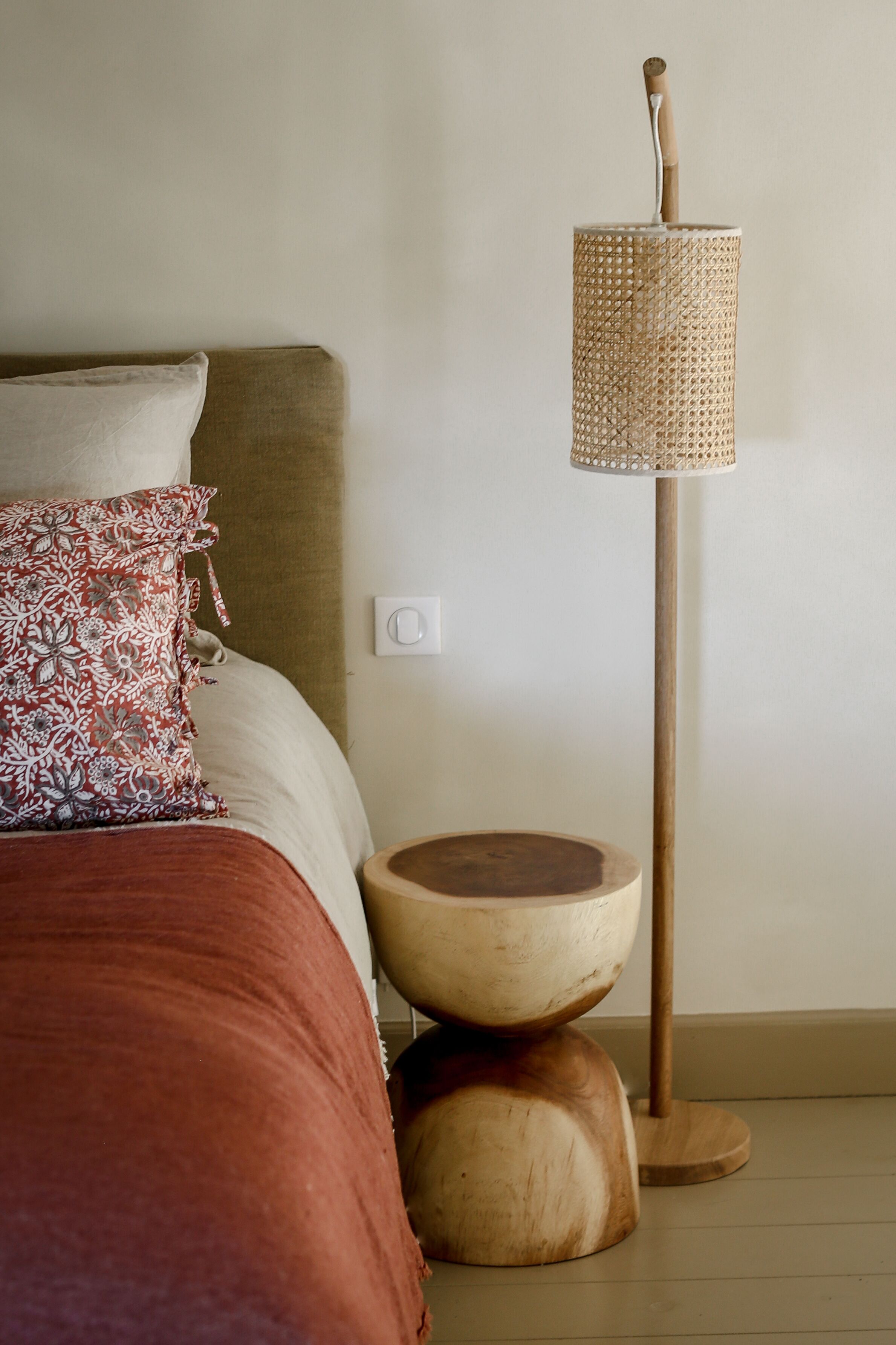 Une chambre à coucher avec un lit, une lampe de chevet et un tabouret en bois.