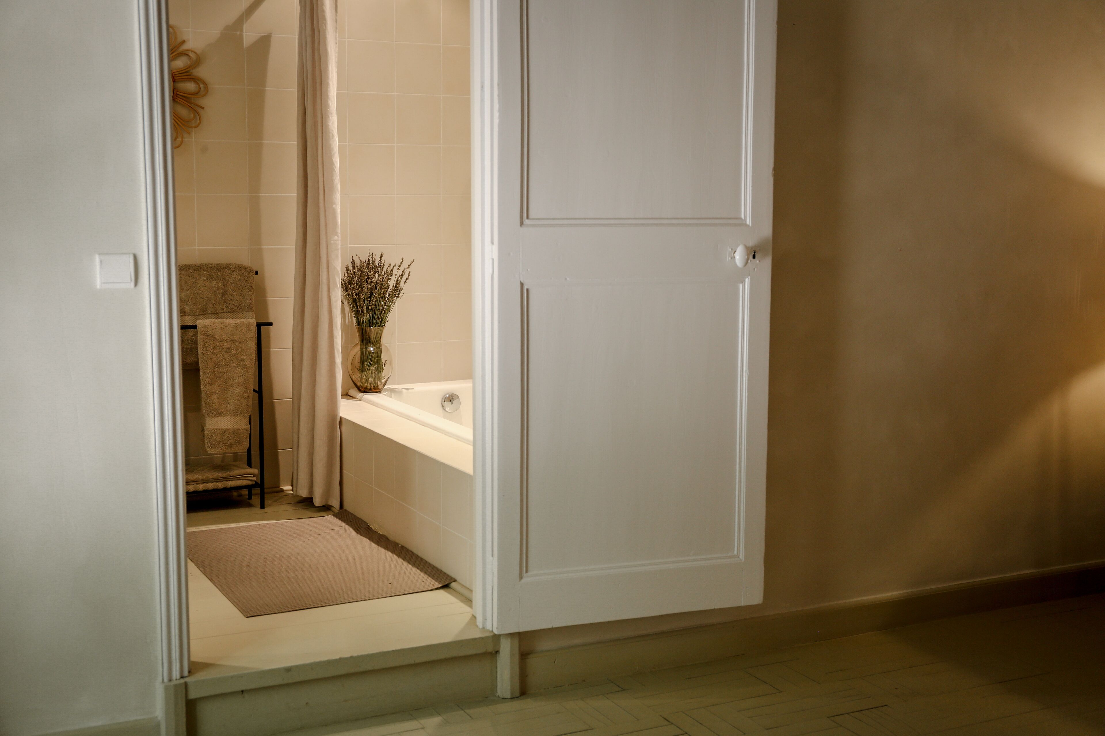 A bathroom with a bathtub, a towel rack, and a small rug.