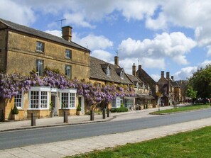 A row of traditional stone buildings with large windows and a street in front.