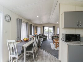 A compact living space with a dining area, a sofa set, a kitchen with a microwave, and a view to the outside.