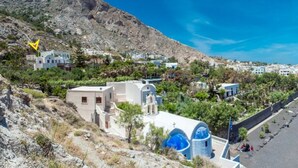 A coastal town with a beach, buildings, and a mountain backdrop. - Moschatos Beach House (Santorini)