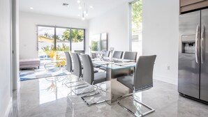 A modern kitchen with a large island, stainless steel appliances, and a dining area with a glass table and chairs. - NEW Townhouse in Coconut Grove (Coconut Grove)