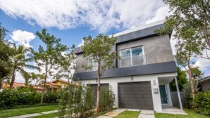 A modern two-story house with a garage, surrounded by a well-maintained lawn and trees. - NEW Townhouse in Coconut Grove (Coconut Grove)