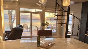 A kitchen with a large island, a dining area with a view of the ocean, and a staircase. - Smith's Lake House 4 bedroom, enjoy spectacular sunrises, 2 bathroom, built 2021 (Penn Yan)