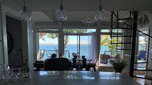 A kitchen with a large island, a dining area with a view of the sea, and a staircase leading to an upper level. - Smith's Lake House 4 bedroom, enjoy spectacular sunrises, 2 bathroom, built 2021 (Penn Yan)