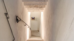 Una stretta scala, scarsamente illuminata, con una ringhiera in metallo e una piccola finestra in alto.