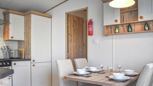 A kitchen with a dining table set for four, equipped with chairs, plates, bowls, and wine glasses. - 2 bedroom accommodation in Robin Hood&rsquo;s Bay (Robin Hood&rsquo;s Bay)