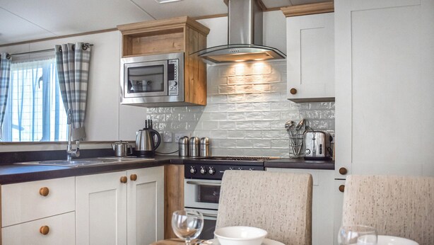 A modern kitchen with a wooden countertop, stainless steel appliances, and a dining area with a table set for two. - 2 bedroom accommodation in Robin Hood&rsquo;s Bay (Robin Hood&rsquo;s Bay)