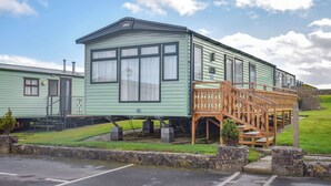 A green mobile home with a wooden staircase and a small porch. - 2 bedroom accommodation in Robin Hood&rsquo;s Bay (Robin Hood&rsquo;s Bay)