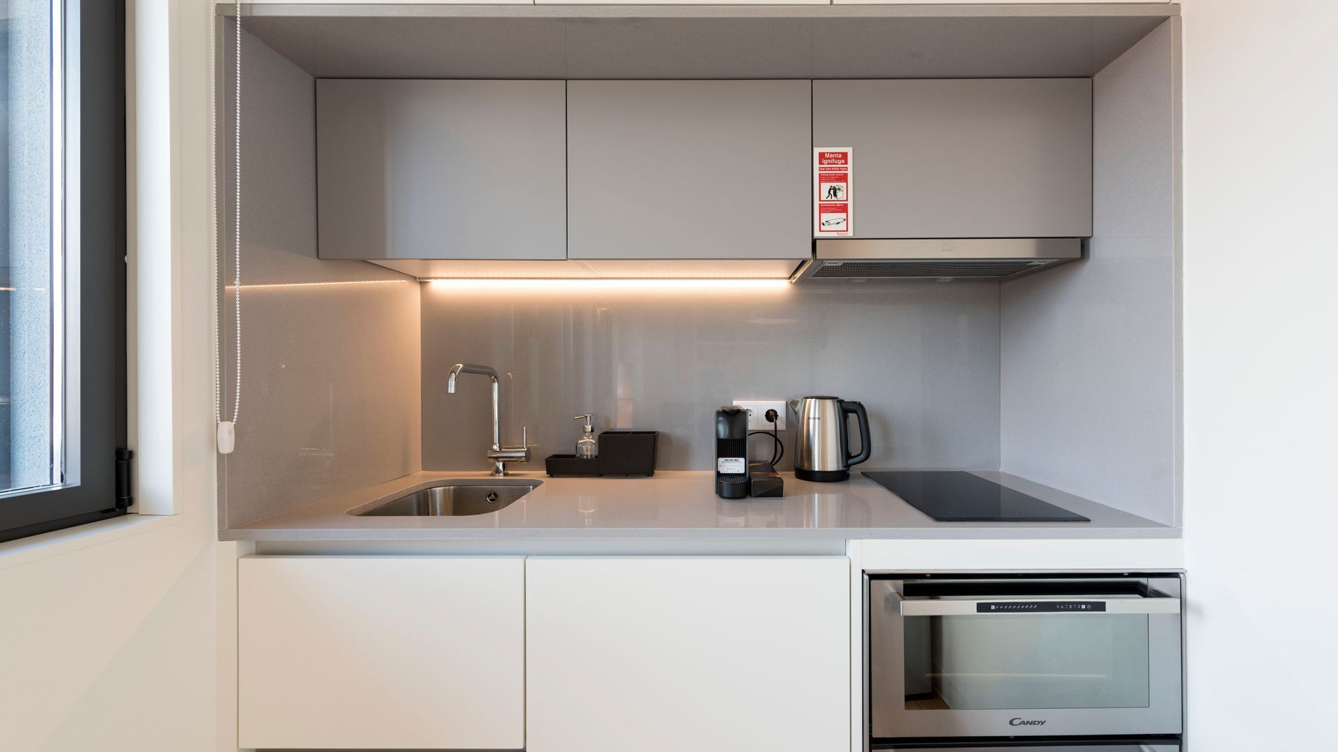A compact kitchenette with a built-in microwave, a coffee maker, and a kettle.