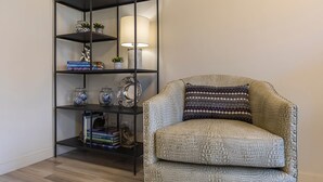 Ein Eckzimmer mit Bücherregal, einer Lampe und einem gemusterten Sessel.