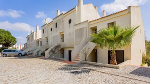 A row of traditional buildings with a cobblestone street, a parked car, and a palm tree. - Gorgeous 2BDR W/Patio & Pool by LovelyStay (Vilamoura)