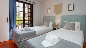 A hotel room with two beds, a large window with curtains, a wall-mounted lamp, and a framed picture. - Gorgeous 2BDR W/Patio & Pool by LovelyStay (Vilamoura)