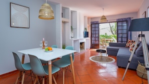 A modern living room with a white table, teal chairs, a gray sofa, and a fireplace. - Gorgeous 2BDR W/Patio & Pool by LovelyStay (Vilamoura)