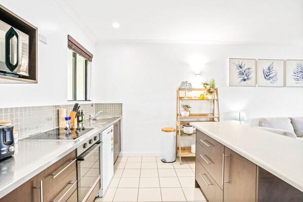 A modern kitchen with a large island, white cabinetry, and a small dining area with a table and chairs.