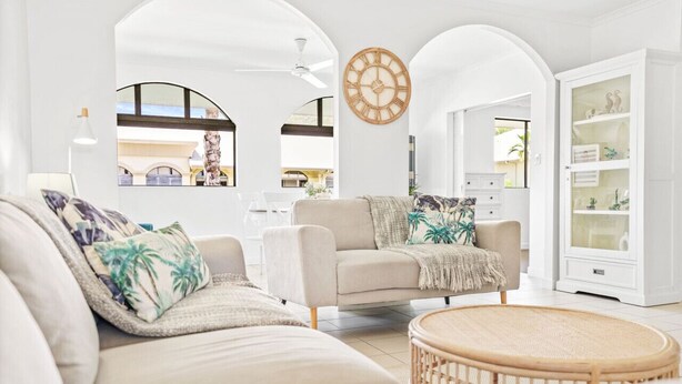 A spacious living room with a beige sofa, a round wicker coffee table, and a white cabinet with glass doors. - Tropical Escape at Mango Lagoon Resort – Spacious 2-Bedroom Apartment with Pools, Palm Cove Charm, and Easy Esplanade Access (Palm Cove)