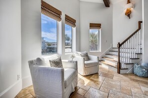 Un vaste espace de vie comprenant un escalier, de grandes fenêtres et une vue sur l’extérieur.