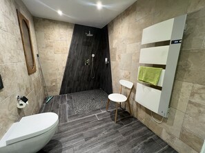 Un baño moderno con inodoro, lavamanos, ducha y toallero.