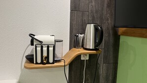 A kitchen area with a wooden shelf holding a kettle, a roll of paper towels, and a container with utensils. - Le Domaine du Verger, Chambres D'hôtes (Osenbach)